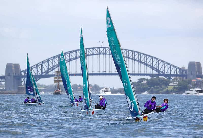 Young sailors racing sailboats on Sydney Harbour with Harbour Bridge in background.