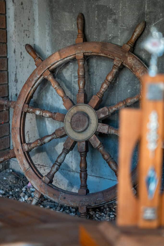 Wooden ship's wheel at Woollahra Sailing Club for maritime decor.