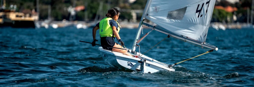 Young sailor sailing a small boat at Woollahra Sailing Club on a sunny day.