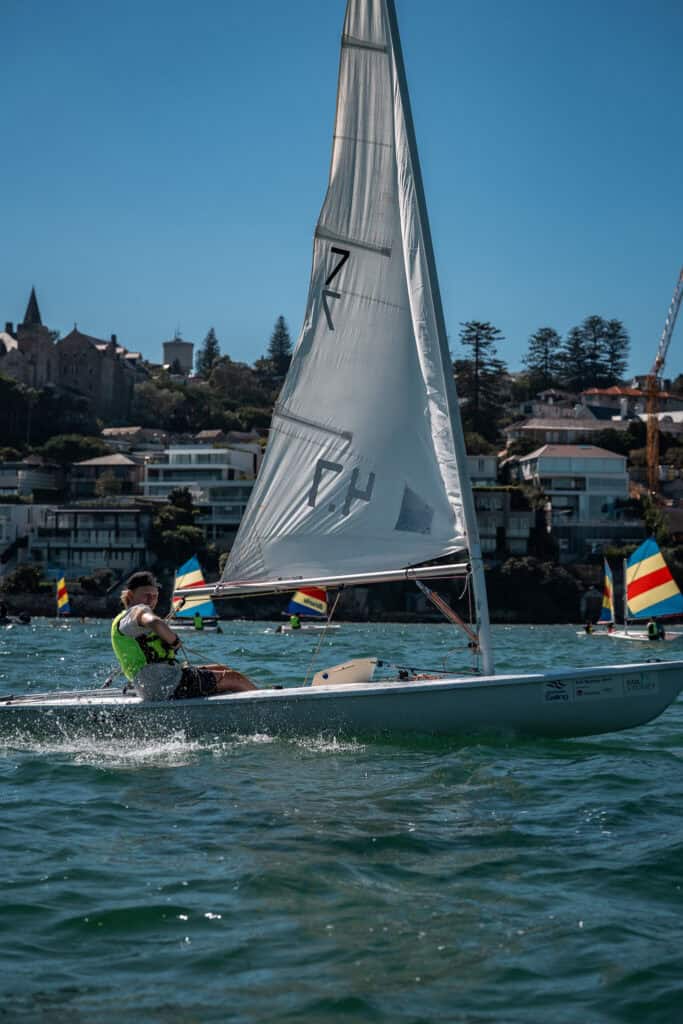 Sailboat racing at Woollahra Sailing Club with scenic background.
