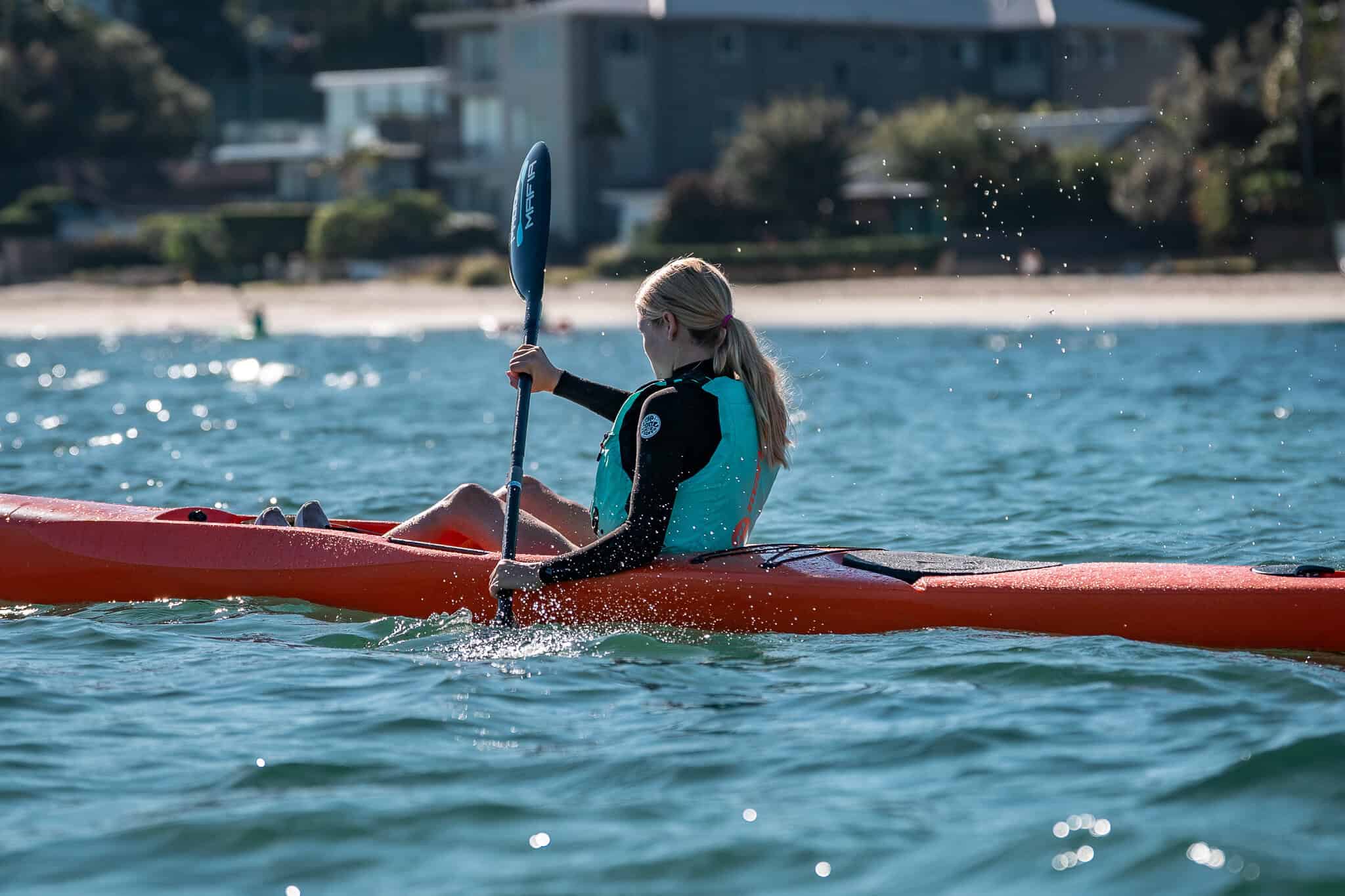 Young woman kayaking at Woollahra Sailing Club on a sunny day.